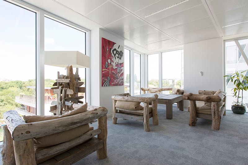 Espace détente des bureaux de Coca-Cola France meublé de fauteuils et d’une table basse en bois brut récupéré