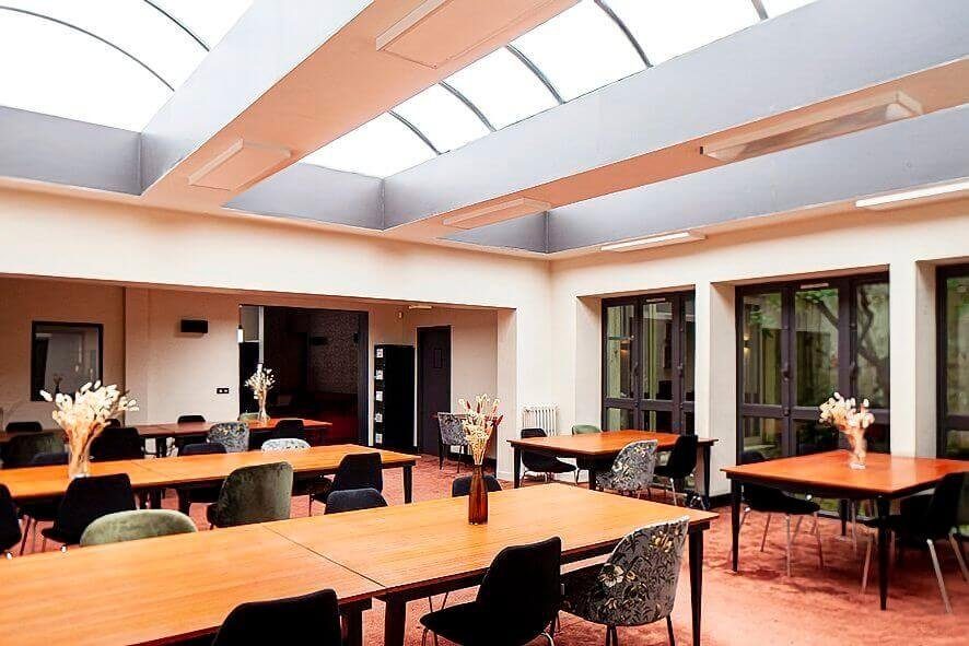 Salle de réunion du Remix Coworking, rue de Turbigo à Paris : table grise entourée de six chaises bleues, parquet, moulures et lustre dans un ancien appartement haussmannien